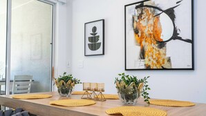 Zona pranzo moderna con tavolo in legno, sedie rivestite di grigio e vasi decorativi con piante.