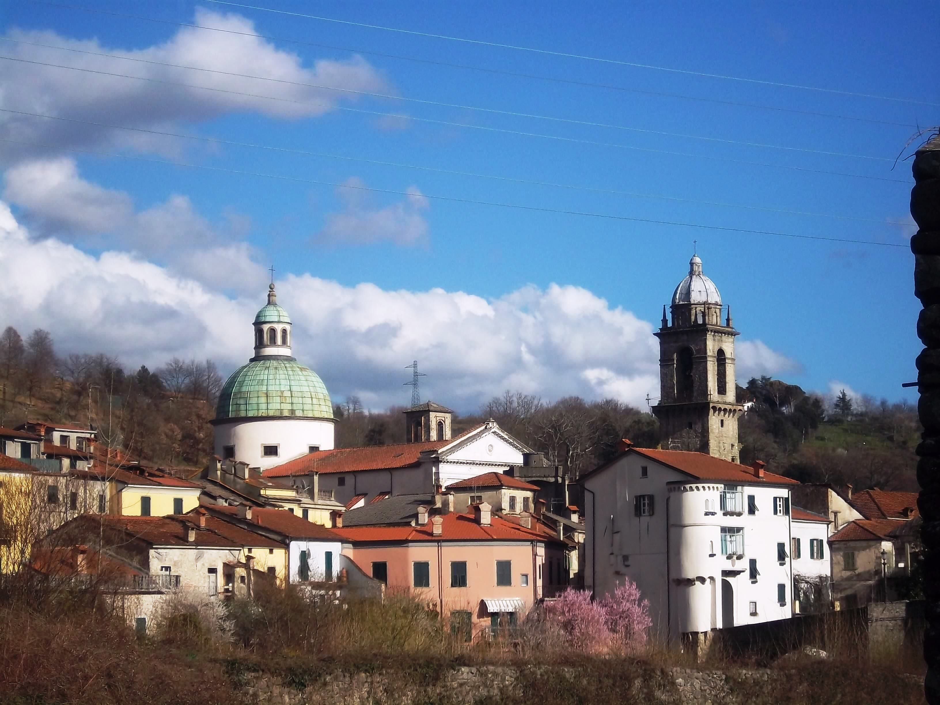 A town with historic buildings, including a church with a dome and a bell tower, surrounded by residential houses.