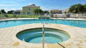 A swimming pool with a hot tub in the center, surrounded by lounge chairs and a fence. - 3BR Home w/ Pool Near Disney (Clermont)