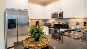 A modern kitchen with white cabinets, stainless steel appliances, a built-in microwave, and a sink. - 3BR Home w/ Pool Near Disney (Clermont)