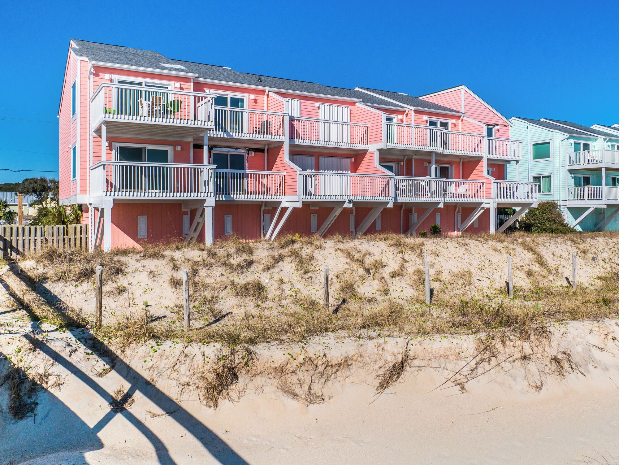 Un hotel frente al mar de varios pisos, con balcones y una playa de arena en primer plano.