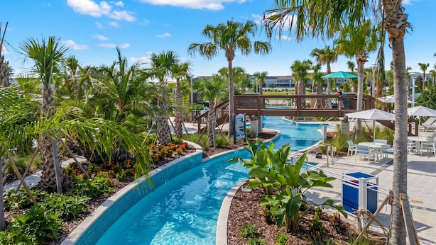 A pool area with palm trees, a wooden bridge, and lounge chairs. - Family 7BR Villa Near Disney & Parks (Clermont)