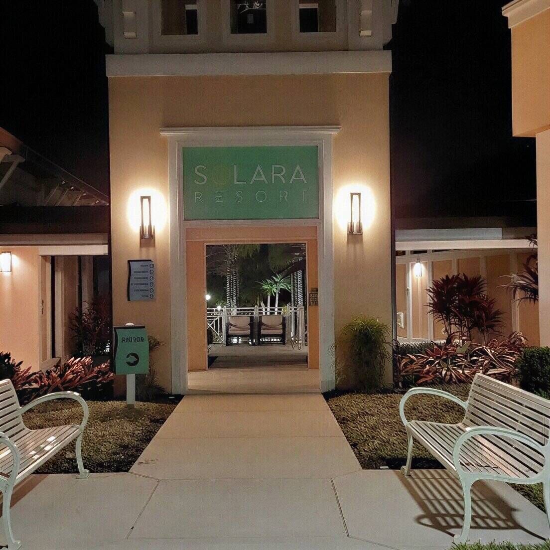 A hotel entrance with a sign reading 'S LARA RESORT,' a covered walkway, and two benches.
