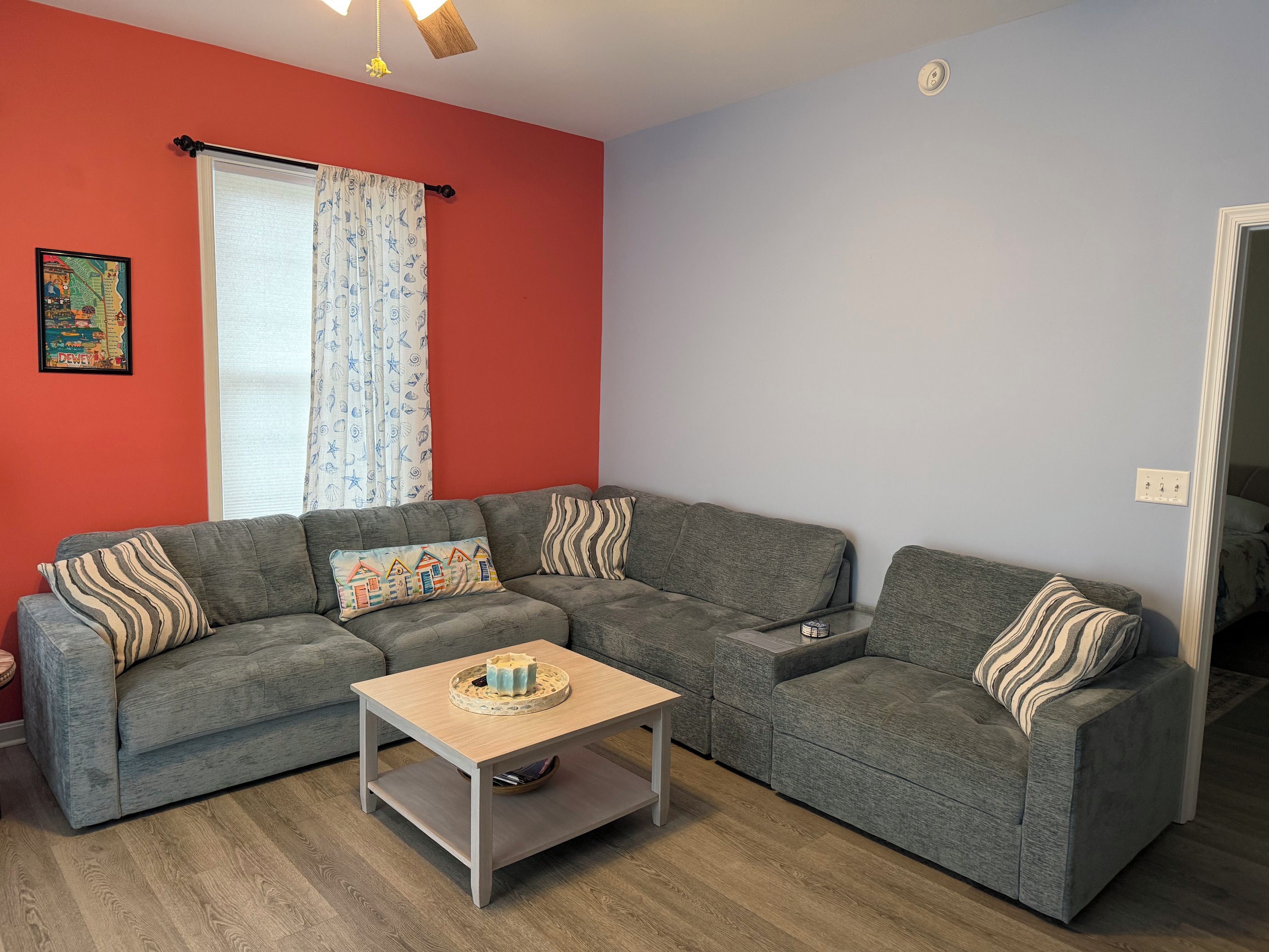 A living room with a grey sofa set, a wooden coffee table, and a red accent wall.