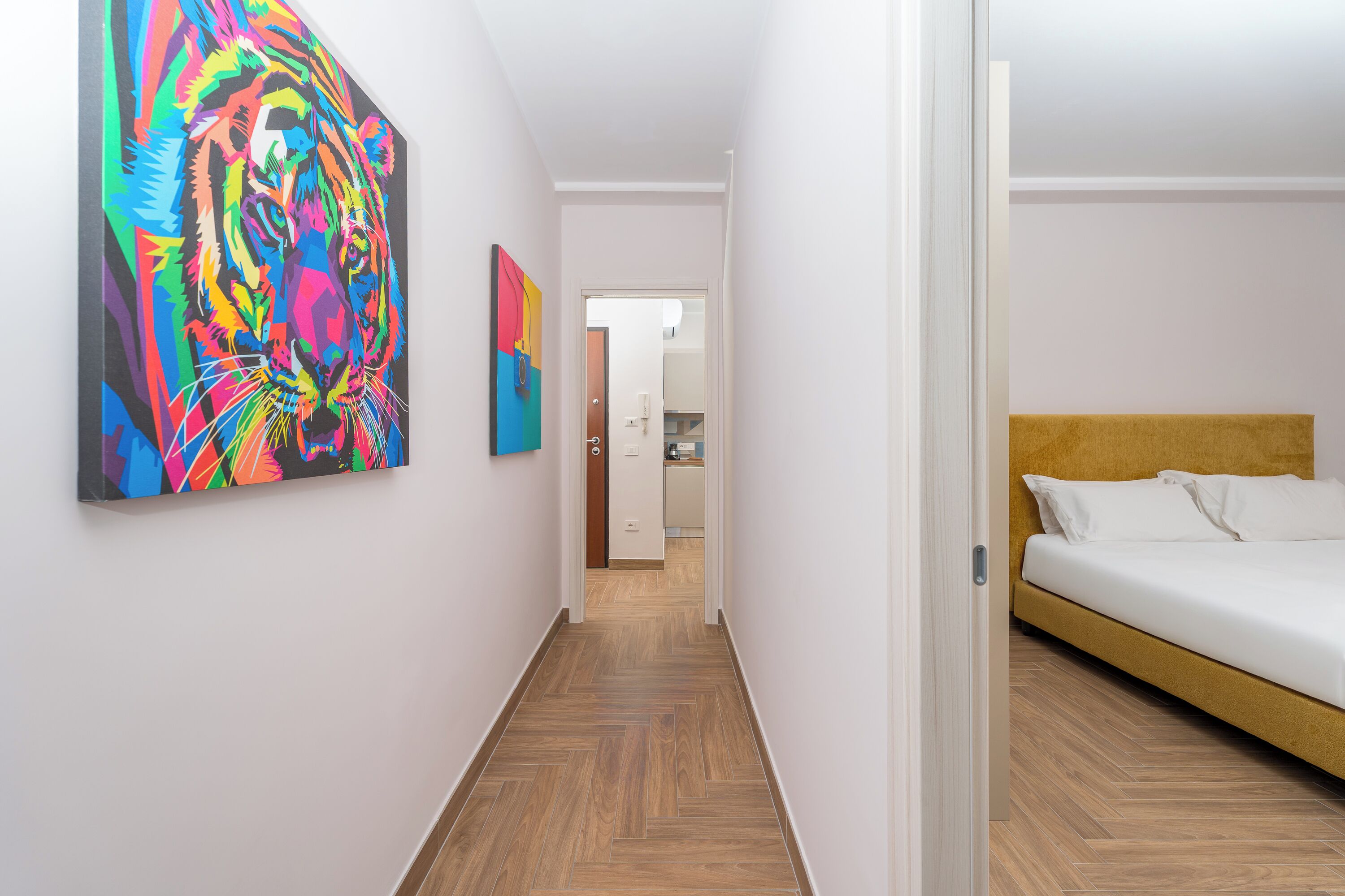 A hallway with a bed and a colorful abstract painting on the wall.