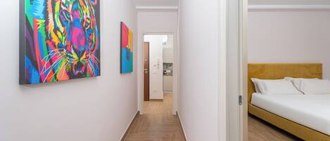 A hallway with a bed and a colorful abstract painting on the wall.