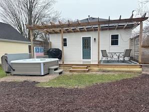 Un patio trasero con jacuzzi, mobiliario de jardín y una pérgola.