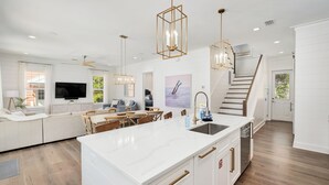 Een moderne keuken met een groot eiland, witte kasten en hanglampen.