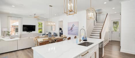 A modern kitchen with a large island, white cabinetry, and pendant lighting.