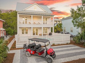 A two-story house with a balcony, a covered patio, and a red golf cart parked in front. - Sunny Side Up | Private Pool/Spa | 6-Seater Golf Cart | Walk to Beach (Santa Rosa Beach)
