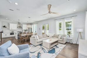 A spacious living area with a large sectional sofa, a coffee table, and a dining area with a table and chairs. - Sunny Side Up | Private Pool/Spa | 6-Seater Golf Cart | Walk to Beach (Santa Rosa Beach)