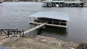 A dock with a covered boat house, a wooden dock, and a gravel area. - 2 bedroom lakefront condo at The Lake of the Ozarks (Lake Ozark)