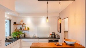 A modern kitchen with white cabinets, a wooden island, and pendant lighting. - Fleur de Sel - Centre de Nantes avec parking (Nantes)