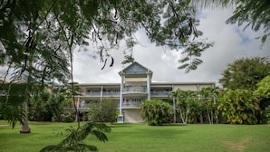 A large building with a central pavilion, surrounded by lush greenery and palm trees. - Le Ti Mahogany - Studio avec Balcon (Saint-Francois)