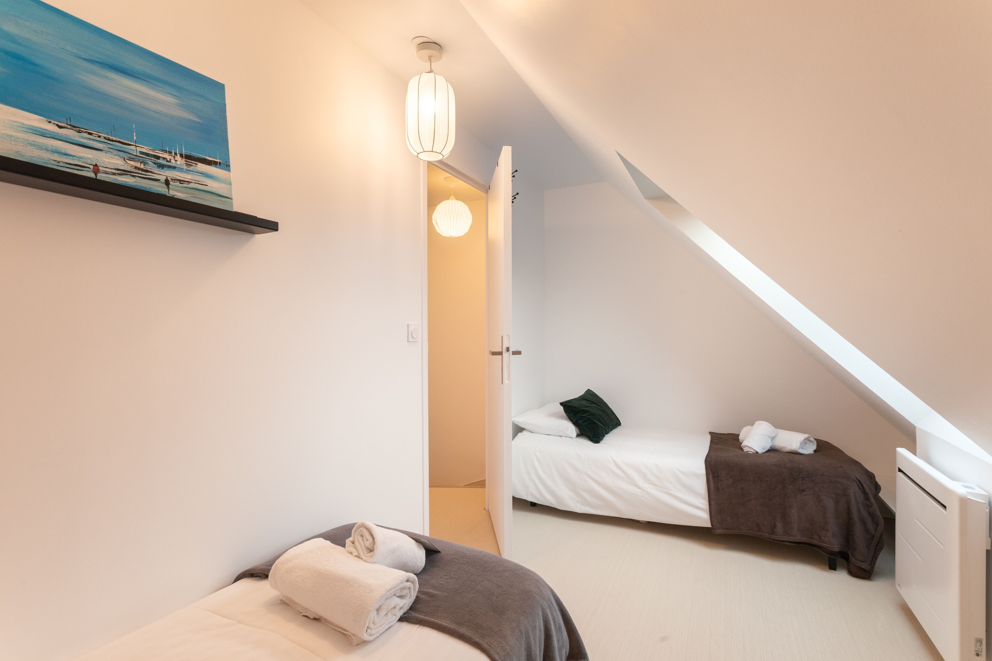 Un dormitorio con dos camas, un cuadro en la pared y una lámpara en el techo.
