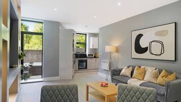 A modern living room with a grey sofa, a coffee table, and a dining area with a table and chairs.