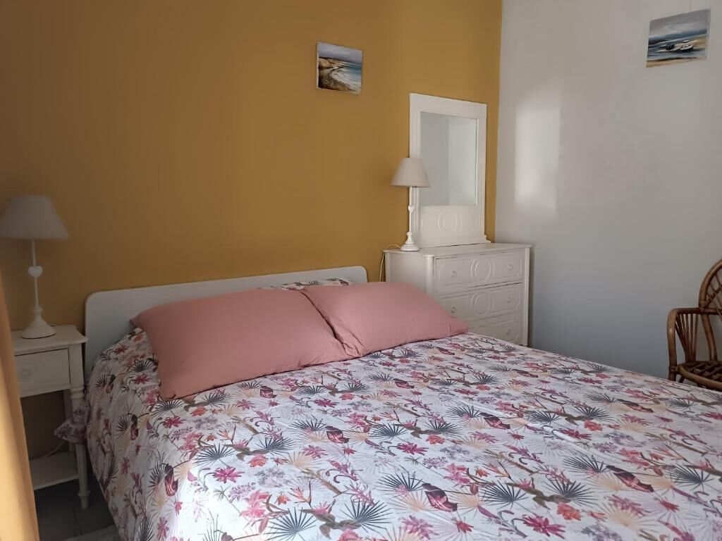 A bedroom with a bed, a nightstand, a dresser, a chair, and a wall with a painting.