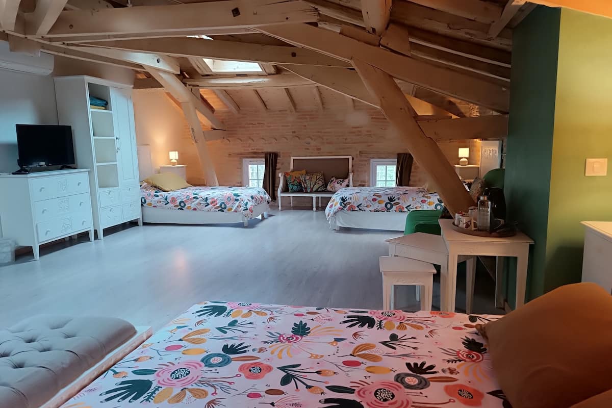 Ein geräumiges Schlafzimmer im Dachgeschoss mit zwei Betten, einem Fernseher und einem Schreibtisch.