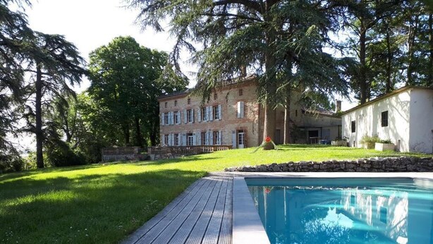 A swimming pool with a wooden deck, surrounded by a grassy lawn and trees. - Le Jardin des Cèdres (Lavaur)