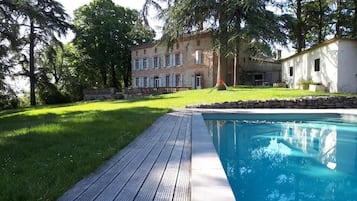 Een seizoensgebonden buitenzwembad en ligstoelen