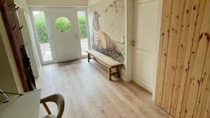 A hallway with a wooden bench, a white door, and a mural on the wall. - Deichkoje12 - Deck 1 vacation apartment directly on the dike with dog | North Sea near (Tönning)