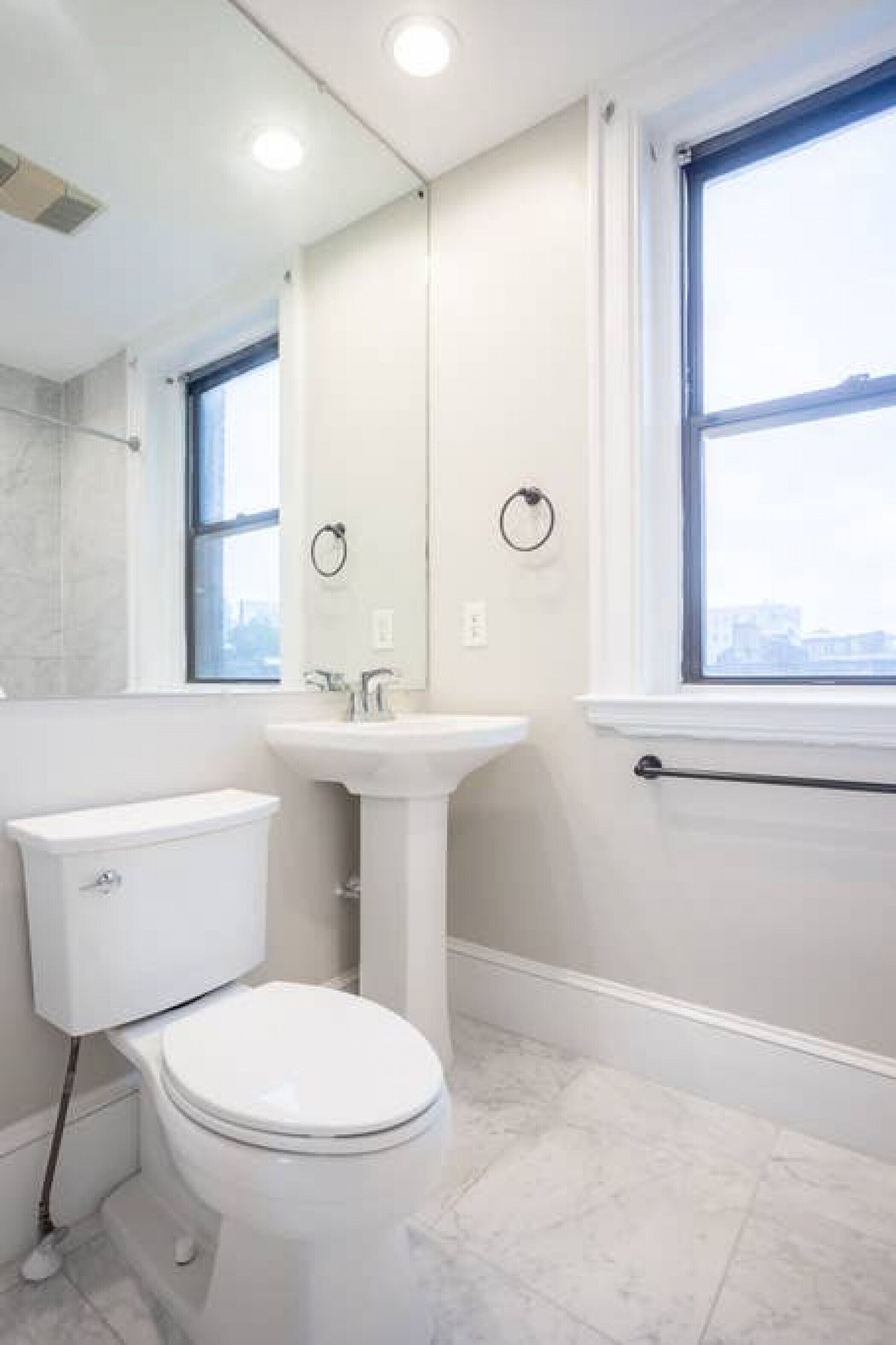 A modern bathroom with a toilet, sink, and window.