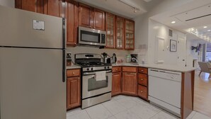 A modern kitchen with wooden cabinets, stainless steel appliances, and a white countertop. - Luxury Home located in Back Bay 8min walk to Fewnway Park, close to Boston University, Berklee & MIT (Boston)