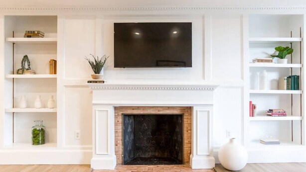 A living room with a fireplace, a mounted TV, and built-in shelving with books and decorative items. - Luxury Home located in Back Bay 8min walk to Fewnway Park, close to Boston University, Berklee & MIT (Boston)
