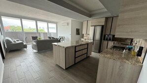 A modern kitchen with a central island, built-in appliances, and a large window providing a view of the outdoors. - Luxury 3BR Penthouse City Mall SPS (San Pedro Sula)
