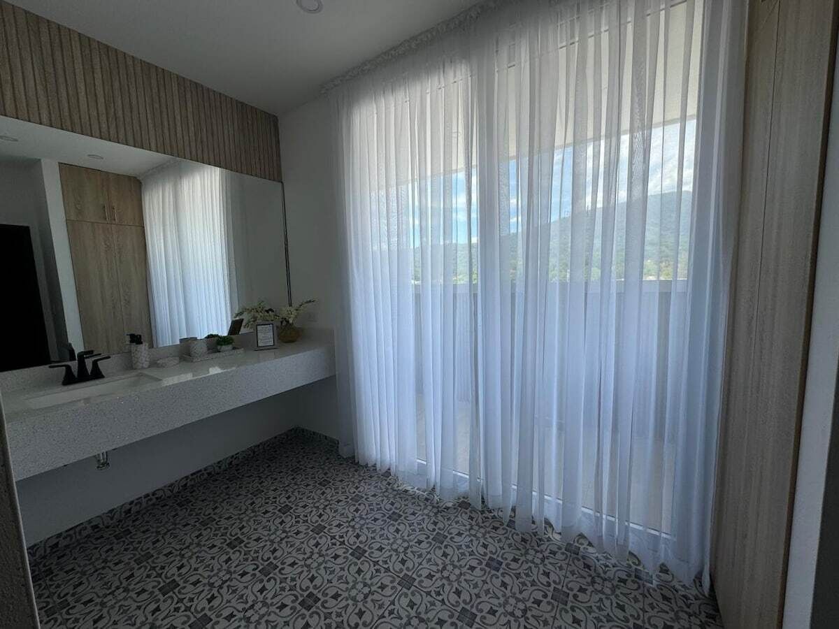 A bathroom with a large mirror, a sink, and a patterned floor.