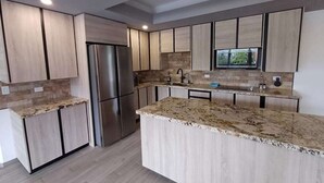 A modern kitchen with a central island, built-in appliances, and a large window. - Luxury 3BR Penthouse City Mall SPS (San Pedro Sula)