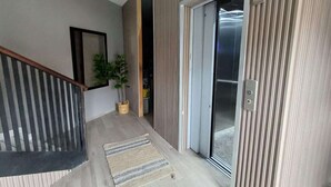 A modern interior with a wooden staircase, a sliding glass door, and a potted plant. - Luxury 3BR Penthouse City Mall SPS (San Pedro Sula)