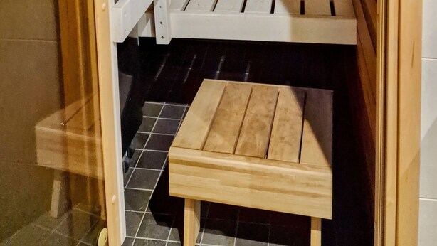 A sauna with wooden benches and a small wooden table.
