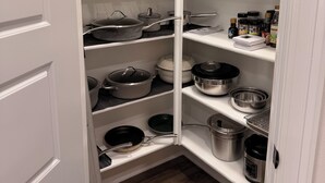 Una despensa bien organizada con estantes llenos de ollas, sartenes y recipientes de almacenamiento.