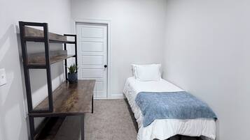 A bedroom with a bed, a desk, and a door.