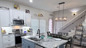 Una cocina moderna con armarios blancos, electrodomésticos de acero inoxidable y una encimera de granito.