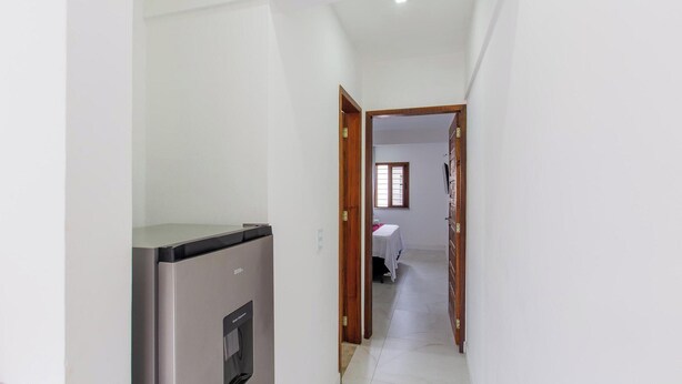 Un couloir étroit avec un distributeur d’eau, une porte donnant sur une pièce avec une fenêtre et un lavabo.