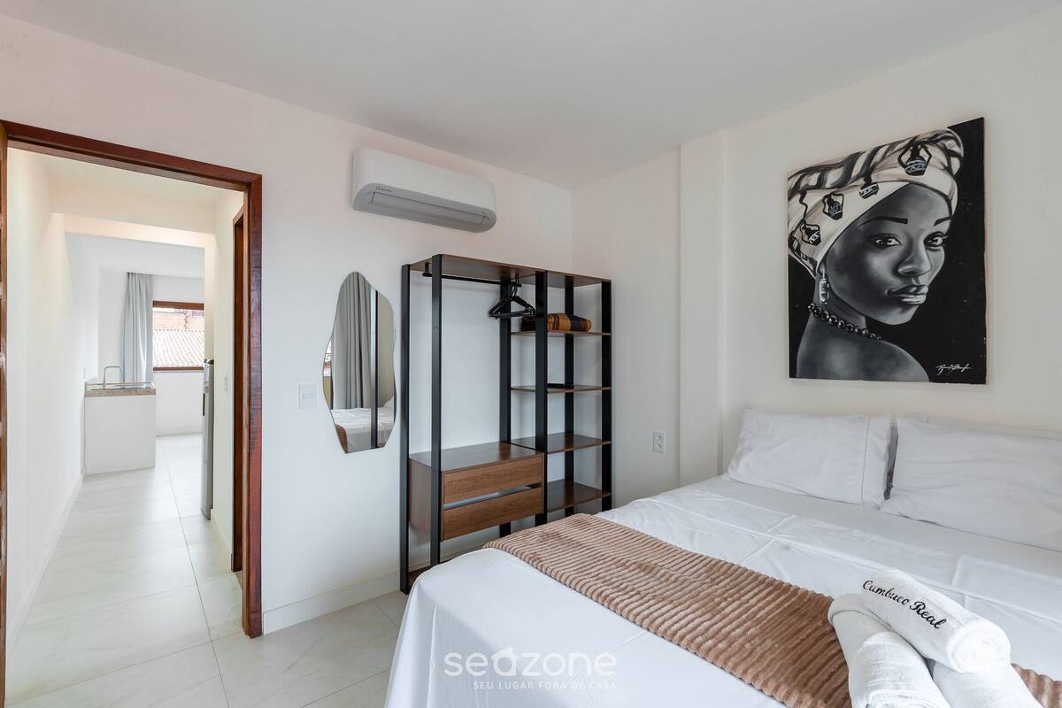 A bedroom with a bed, a wardrobe, a mirror, and a painting on the wall.