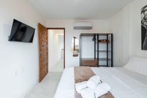 Ett hotellrum med en säng, en tv, en garderob och en spegel.