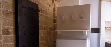 A spa area with a stone wall, a large painting, a wooden stool, a white cabinet, and a bathtub.