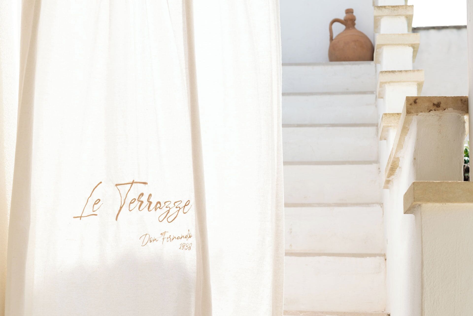 A staircase with a white wall and a sign reading "Le Terrazze Don Fernando 1988".