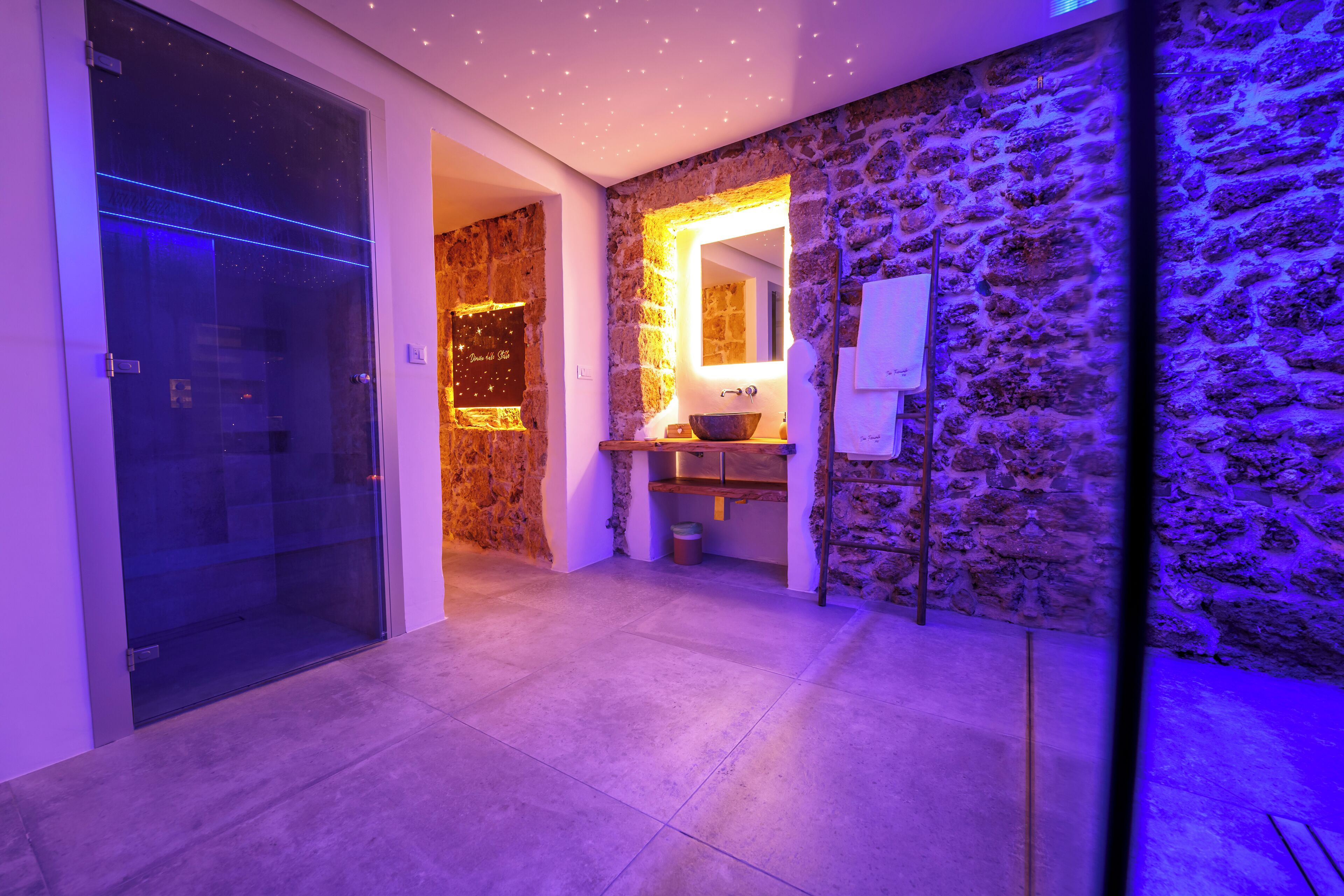 Ein modernes Badezimmer mit Steinwand, Glastür und Waschbecken mit Schale.