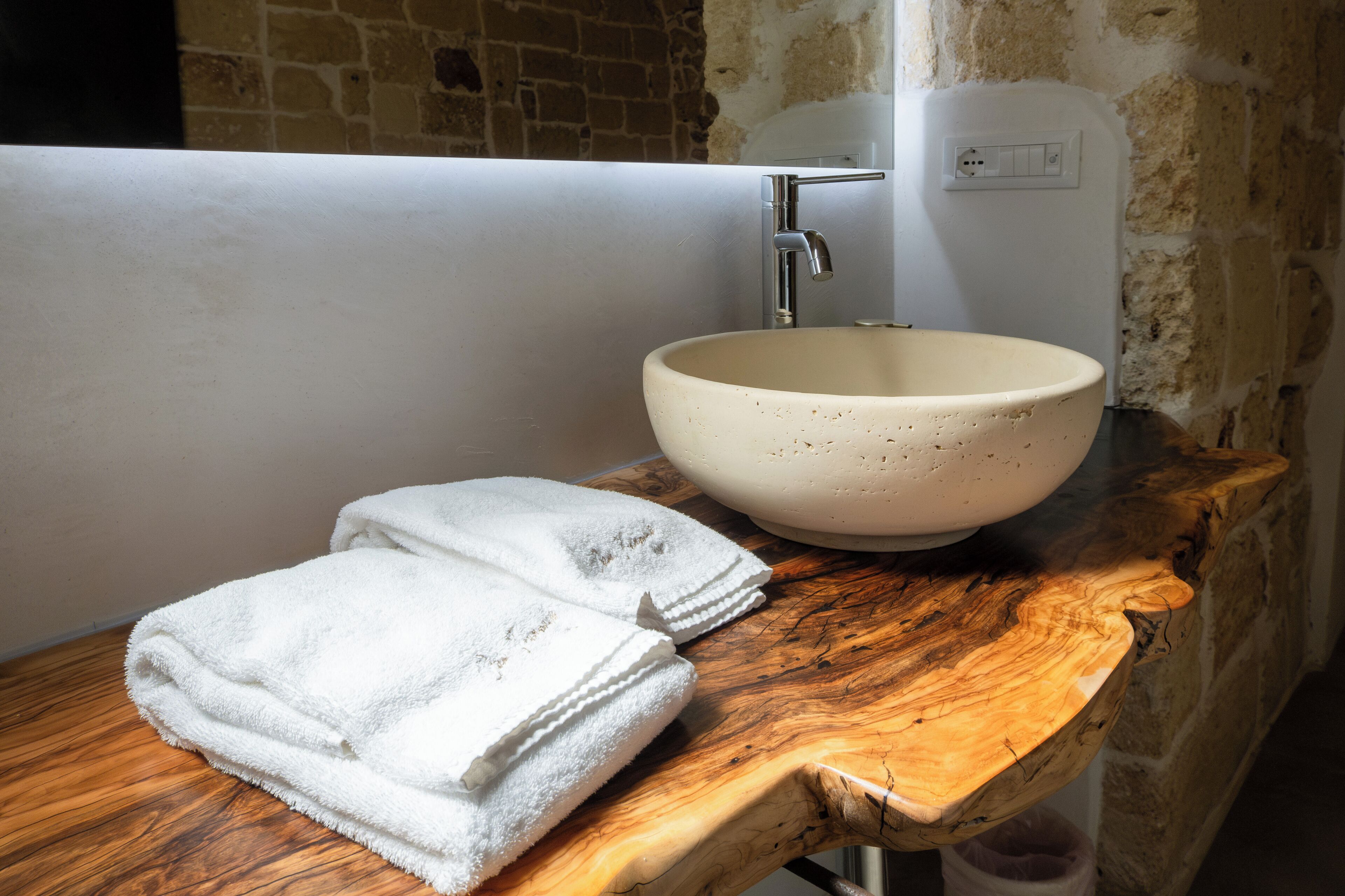 A bathroom with a wooden vanity, a white sink, and a towel.