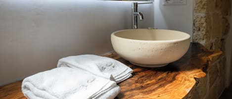 A bathroom with a wooden vanity, a white sink, and a towel.