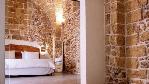 Ein Schlafzimmer mit Steinwand, einem Bett und einem kleinen Pool.