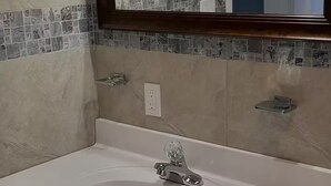 A bathroom with a white sink, a mirror with a wooden frame, and a tiled backsplash. - Sunset At Chalvilles - Peaceful 2-bedroom house with AC in The Valley (East End Village)