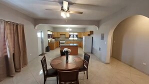 A dining area with a round table, chairs, and a ceiling fan. - Sunset At Chalvilles - Peaceful 2-bedroom house with AC in The Valley (East End Village)