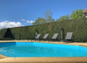 A swimming pool with four lounge chairs and a wooden deck. - Gîte des Grotteaux (Huisseau-sur-Cosson)