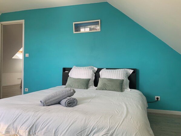 A bedroom with a bed, two pillows, a rolled towel, and a small window. - Gîte des Grotteaux (Huisseau-sur-Cosson)