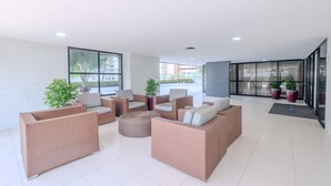 Un espace intérieur vaste et lumineux, aménagé avec des meubles en osier, de grandes fenêtres et des plantes en pot.